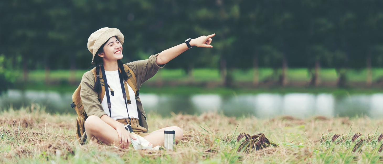 Young woman travel nature summer trips. Asia people tourism sitting on nature park pointing
